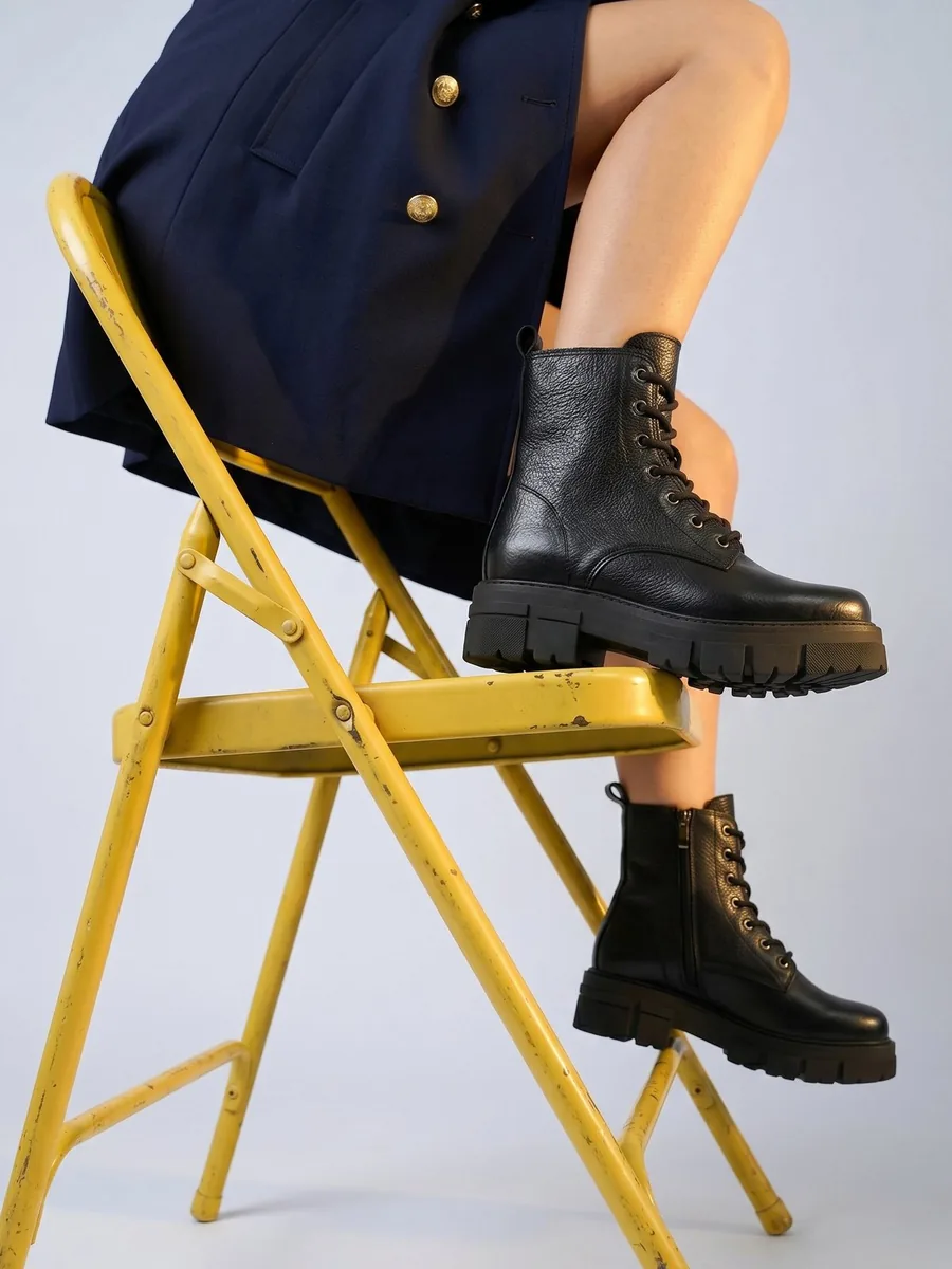 Schwarze Schnürboots mit grober Profilsohle von Apple of Eden auf einem gelben Stuhl