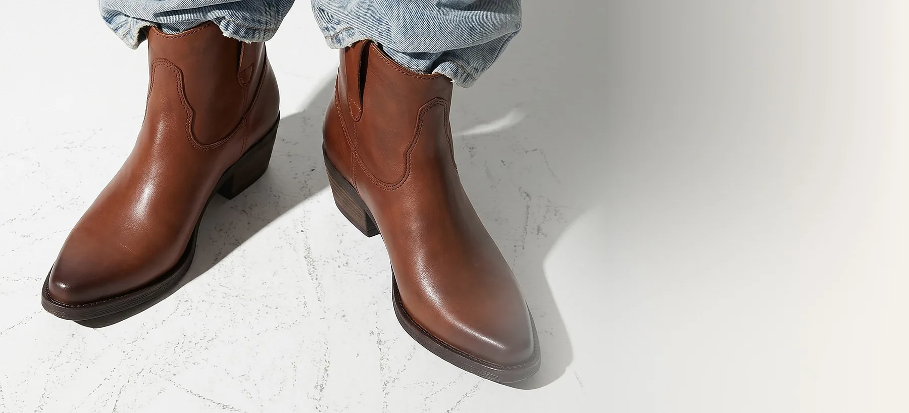 Frau in heller Jeans trägt Evie Camel, eine Western-Stiefelette aus camelfarbenem Glattleder von Apple of Eden